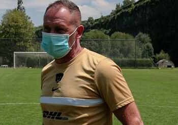 Persona entrenando con mascarilla en campo de césped al aire libre.