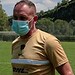 Persona entrenando con mascarilla en campo de césped al aire libre.