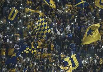 Afición apoyando con banderas y luces en estadio de fútbol en México.