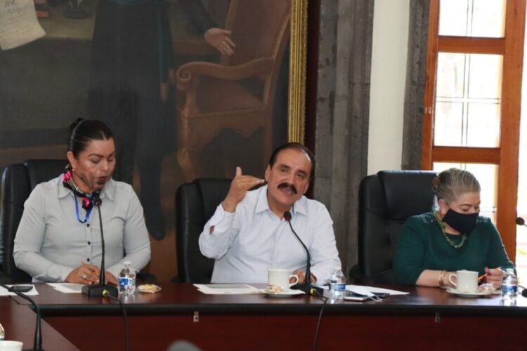 Profesores y autoridades en reunión formal en un espacio de oficina.