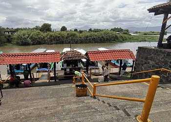 Barco turístico en muelle de río con turistas y embarcaciones, paisaje natural, turismo en México.