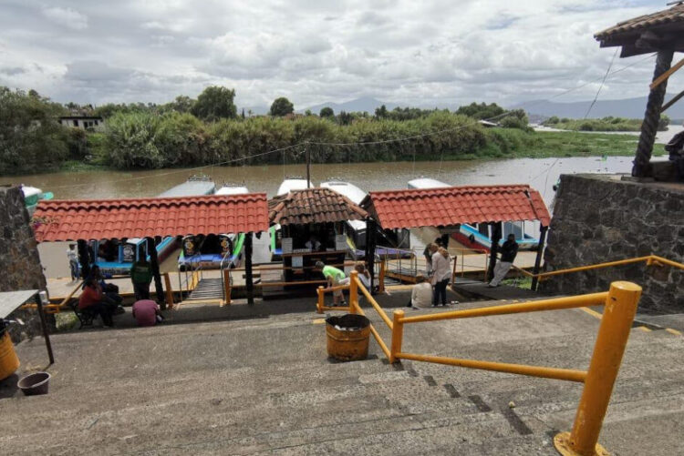 Barco turístico en muelle de río con turistas y embarcaciones, paisaje natural, turismo en México.