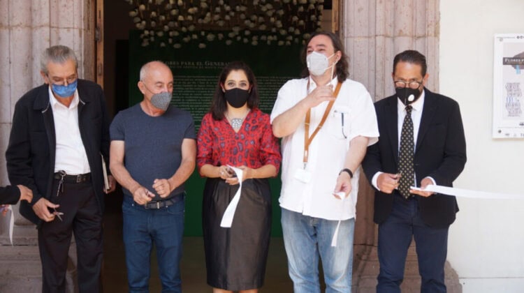 Diversos profesionales en evento de apertura con mascarillas y documentos, en un entorno formal y cultural.