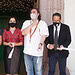 Diversos profesionales en evento de apertura con mascarillas y documentos, en un entorno formal y cultural.