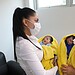 Nina recibiendo atención médica con madres con mascarillas, bebés envueltos en mantas amarillas.