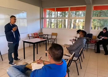 Estudiante presentando en aula con otros alumnos, aula moderna con vista a la naturaleza, ambiente de aprendizaje tranquilo y innovador.
