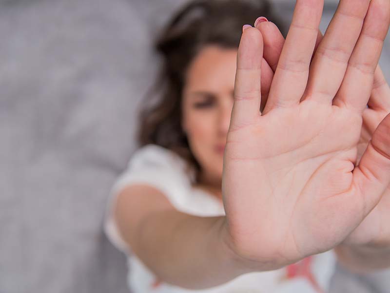 Young woman showing her denial with NO on her hand. Focus on hand. Timid woman symbol of violence in the family
