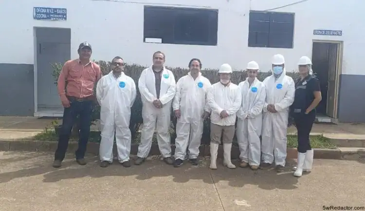 Personal de salud y construcción en exteriores, grupo con equipo de protección en entorno institucional.