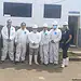 Personal de salud y construcción en exteriores, grupo con equipo de protección en entorno institucional.