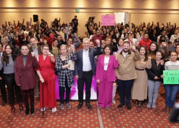 Celebración y apoyo en evento de mujeres, con oradores y participantes uniendo fuerzas.