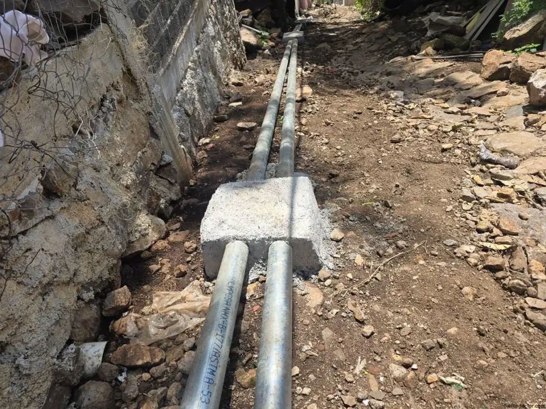 Tuberías de agua en obra de calle pavimentada con tubería de concreto y accesorios de acero galvanizado.