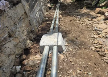 Tuberías de agua en obra de calle pavimentada con tubería de concreto y accesorios de acero galvanizado.