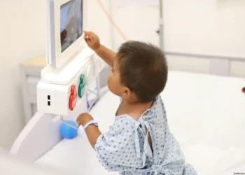 Niño en hospital usando monitor médico para diagnóstico.
