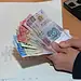 Dinero en efectivo de diferentes denominaciones en manos humanas en oficina moderna.
