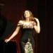 Jazzwoman tocando piano en escenario con vestido floral elegante.