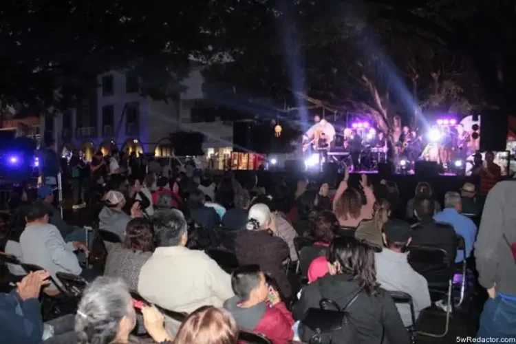 Concierto en vivo en la noche con público disfrutando música y luces en un espacio al aire libre.