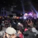 Concierto en vivo en la noche con público disfrutando música y luces en un espacio al aire libre.