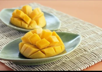 Jugosidad de mango fresco cortado en cubos en platos verdes, para postres y meriendas saludables.
