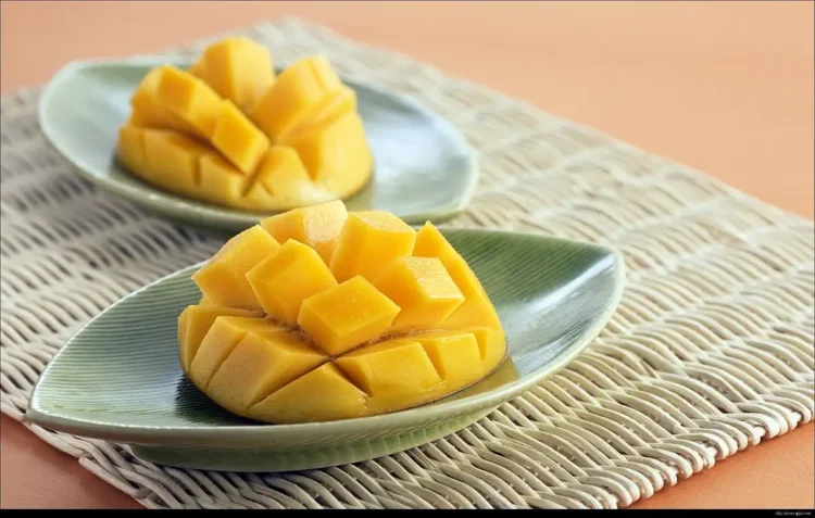 Jugosidad de mango fresco cortado en cubos en platos verdes, para postres y meriendas saludables.