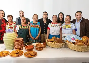 Personas celebrando con comida tradicional mexicana en evento cultural.