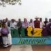 Personas en la plaza tourism en Tonquie, Chiapas, México, con letras decorativas y paisaje natural de fondo.