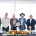 Reconocimiento empresarial presentado en evento formal con ejecutivos y un representante con sombrero cowboy.