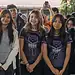 Chicas jóvenes en uniforme deportivo en evento escolar con otros estudiantes en el fondo.