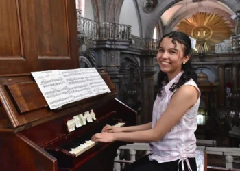 Pianista joven tocando en iglesia histórica durante evento cultural en Michoacán.