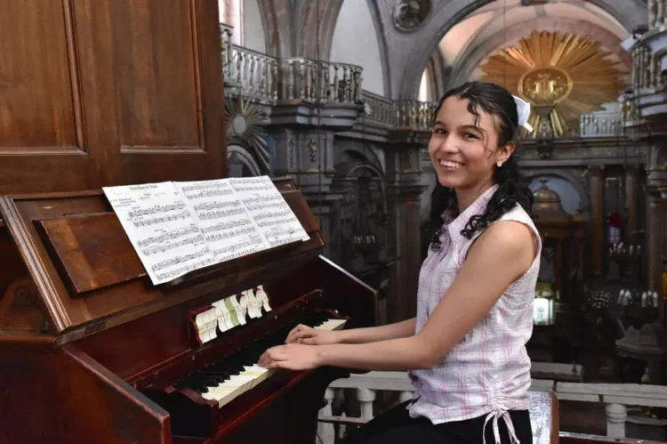 Pianista joven tocando en iglesia histórica durante evento cultural en Michoacán.