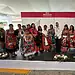 Vestido tradicional mexicano en un evento cultural con grupo de personas en un escenario.