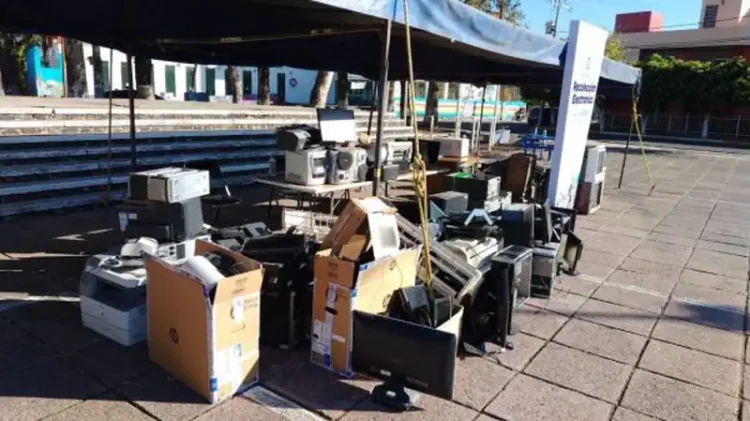 Basurero con computadoras y electrónicos usados en una plaza pública.