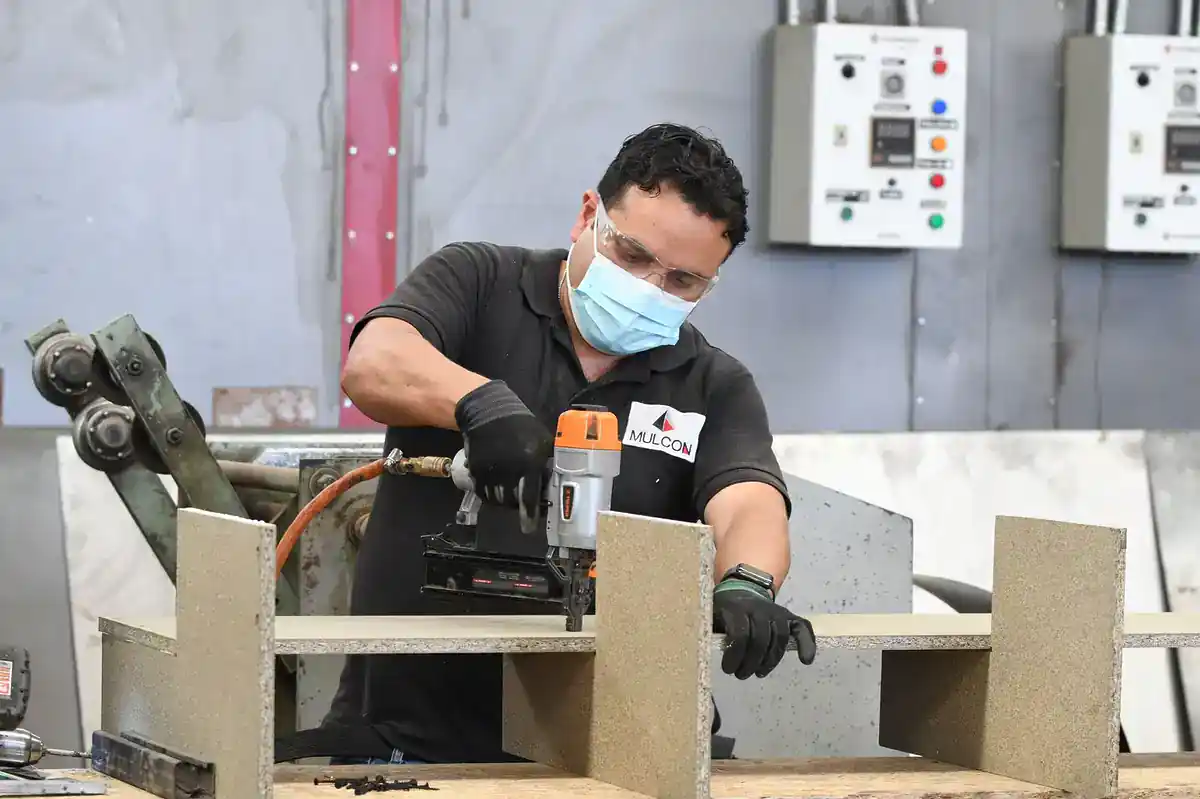 Cortadora de madera en taller industrial con trabajador usando equipo de protección.
