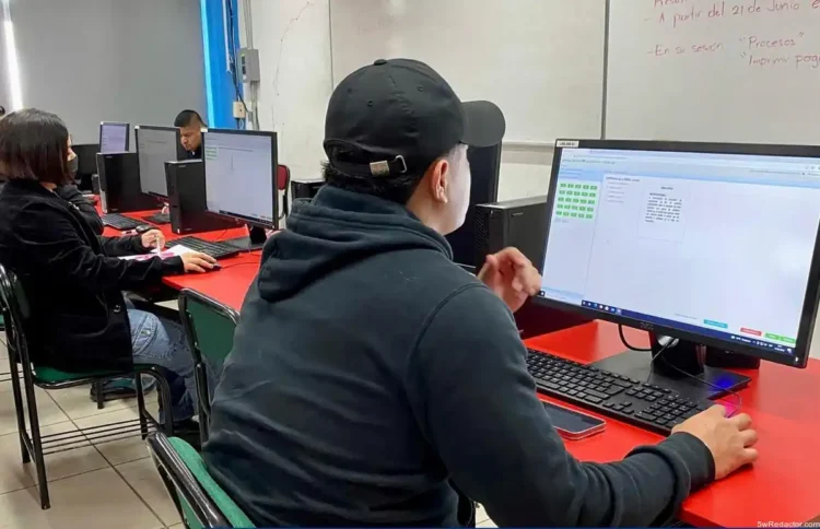 Aprendizaje en aula de informática con estudiantes usando computadoras y software de gestión.
