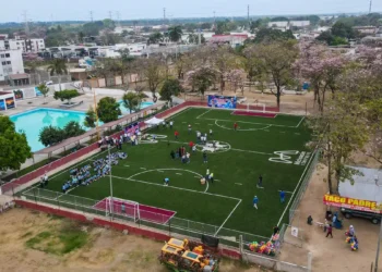 Cancha de fútbol 7 en Michoacán con jugadores y espectadores en un evento comunitario.