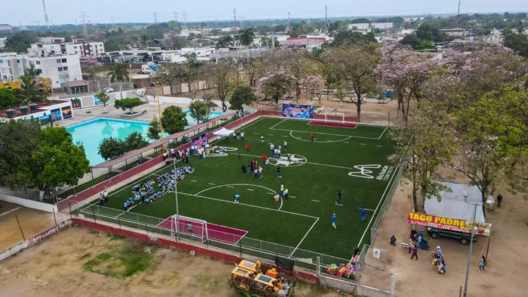 Cancha de fútbol 7 en Michoacán con jugadores y espectadores en un evento comunitario.