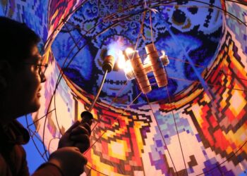 Un artista manipula fuego en un espectáculo vibrante durante un festival cultural en Michoacán. La escena combina arte y trad.