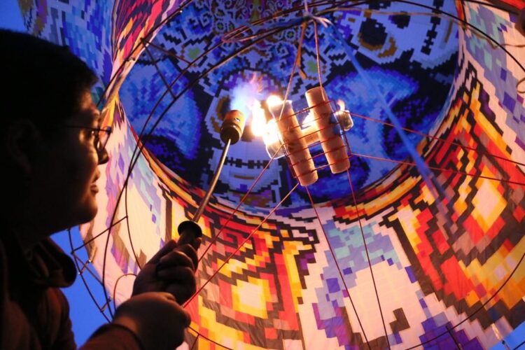 Un artista manipula fuego en un espectáculo vibrante durante un festival cultural en Michoacán. La escena combina arte y trad.