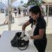 Persona revisando una maleta en un puesto de control en un evento al aire libre.