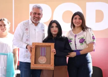 Joven michoacana posa con el premio Presea Eréndira en reconocimiento a su talento en física, acompañada por autoridades en u.