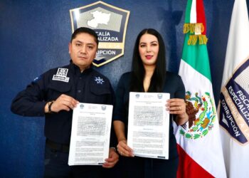 Policía y funcionaria muestran documentos en acto oficial.