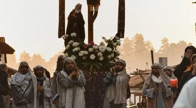 Procesión de Semana Santa en Michoacán con crucifijo y feligreses en vestimenta tradicional en un evento religioso.