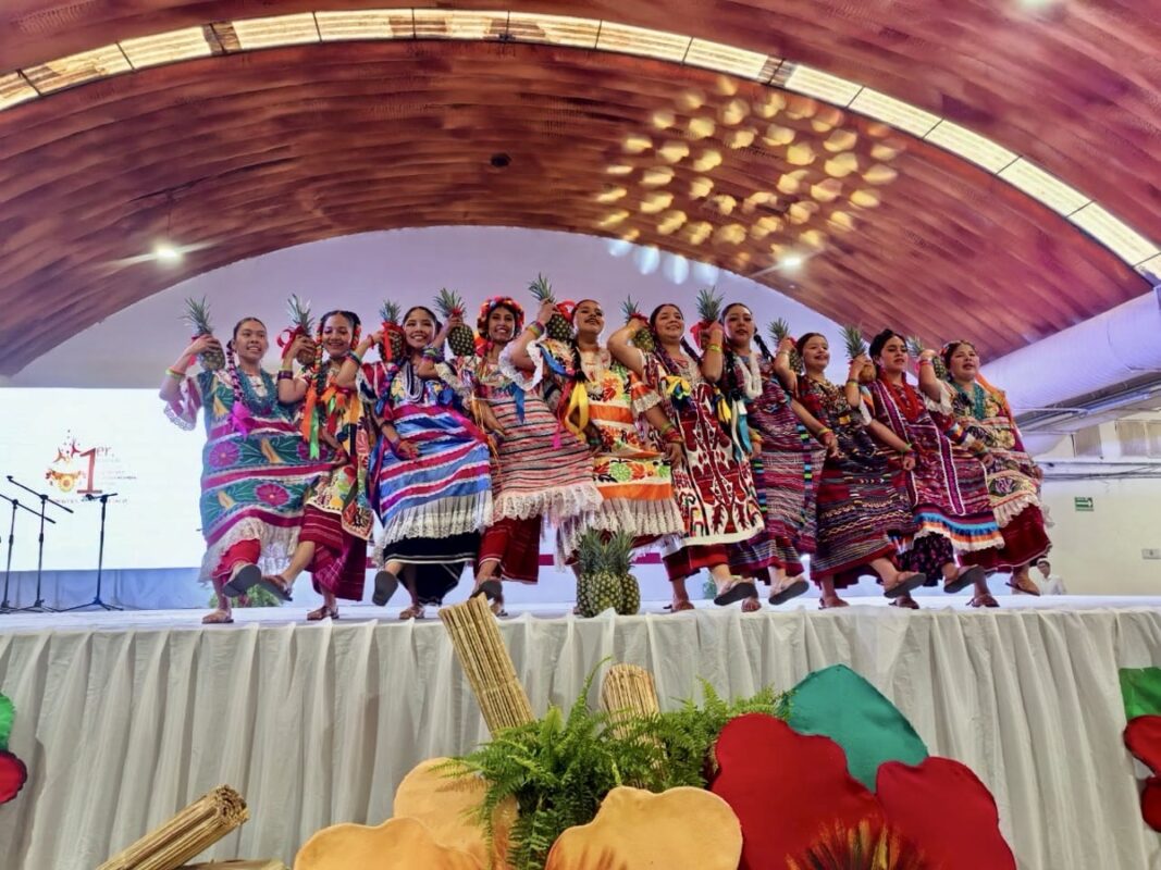 Jóvenes en trajes tradicionales bailan en escenario durante festival cultural en Michoacán.