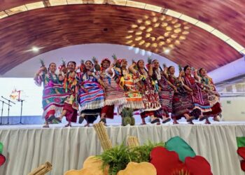 Jóvenes en trajes tradicionales bailan en escenario durante festival cultural en Michoacán.