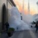 Fumigación en Zamora para prevenir el dengue en templos, con presencia de humo y personal de control de plagas en una calle h.