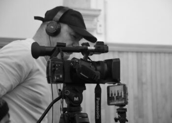 Cámara profesional de cine con operador ajustando el enfoque en un set de grabación.