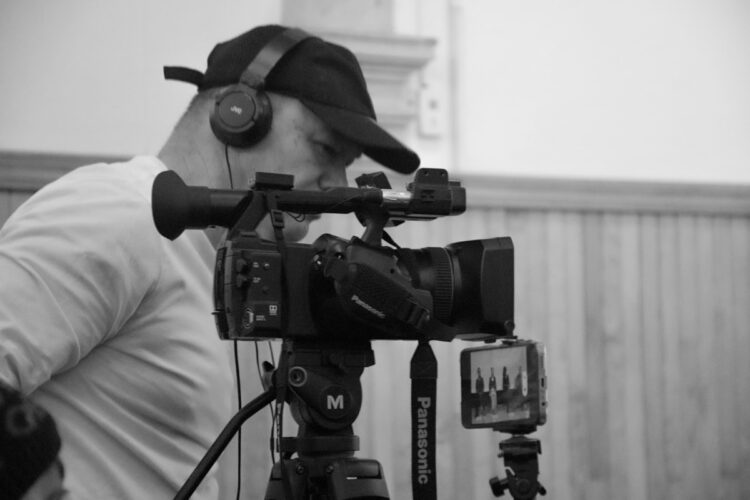 Cámara profesional de cine con operador ajustando el enfoque en un set de grabación.