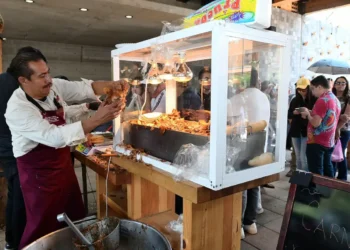 Carne asada en puesto callejero durante evento en Michoacán con público disfrutando.