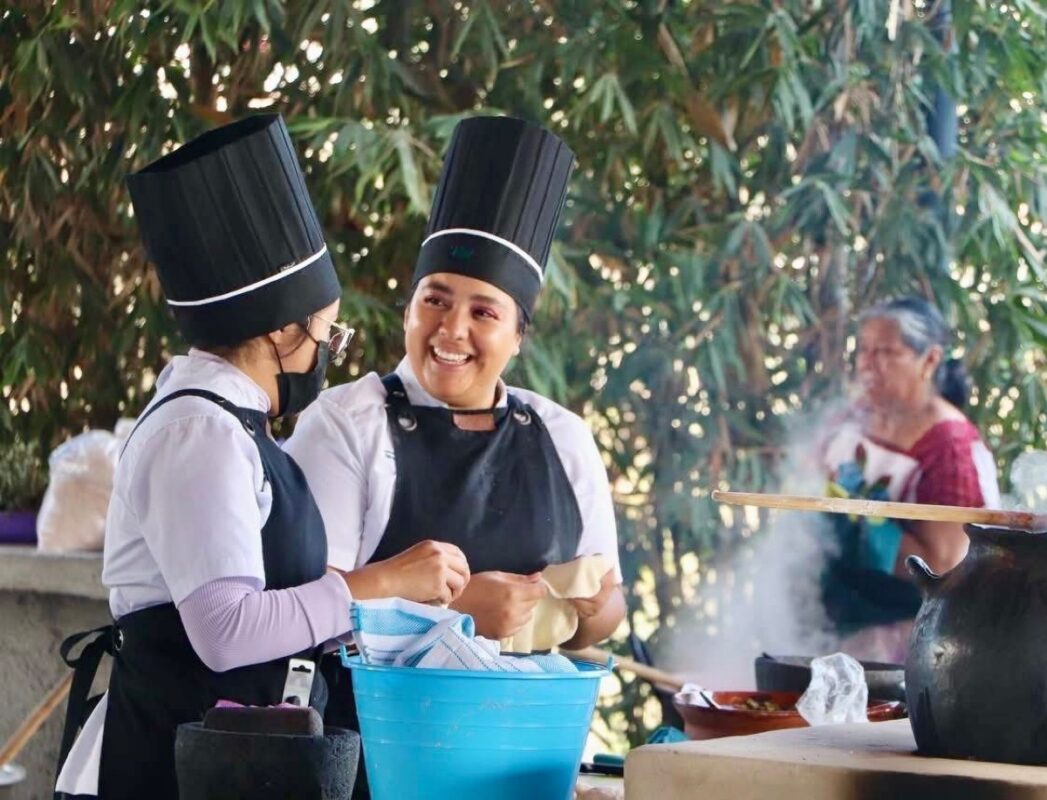Estudiantes en uniformes de chef conversan en un entorno al aire libre, promoviendo nuevas carreras universitarias en Aquila.