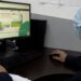 Persona usando computadora con pantalla de plataforma digital de certificación cárnica en oficina.