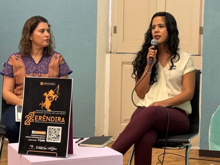 Mujer hablando en evento cultural con micrófono en mano.
